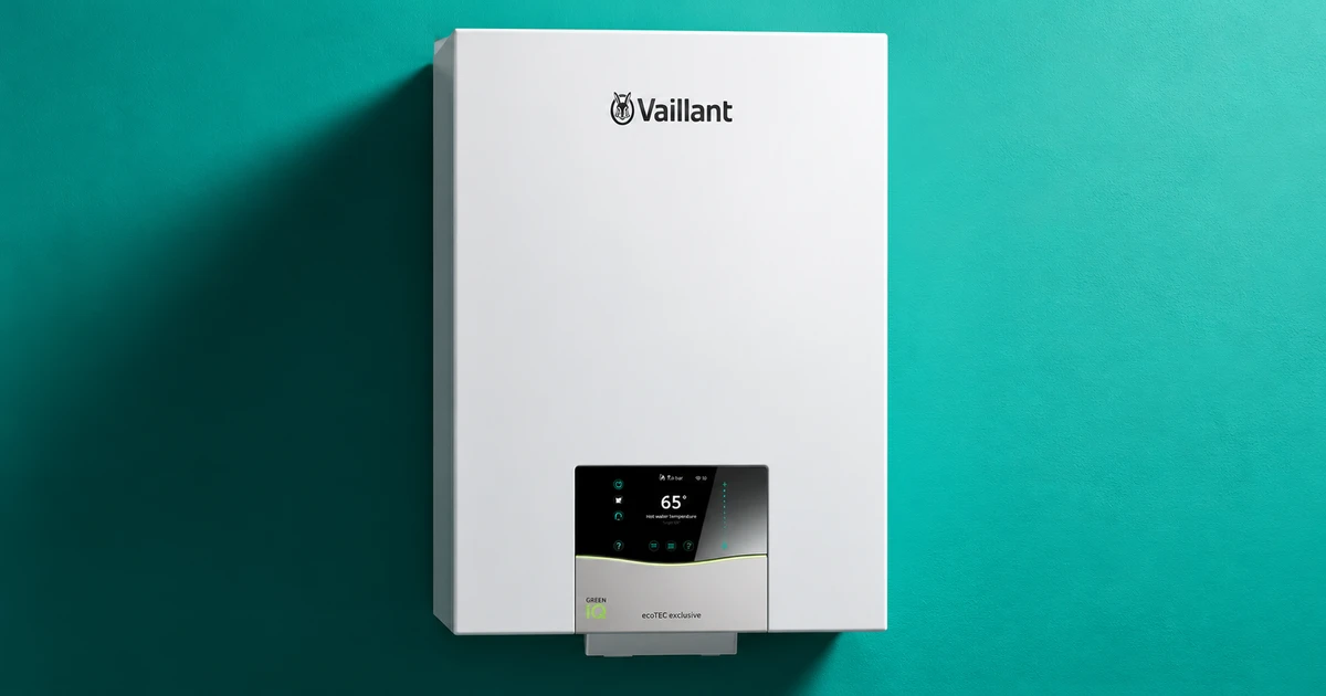 White Vaillant ecoTEC exclusive boiler installed on a teal wall, its digital display showing 65° hot water temperature.