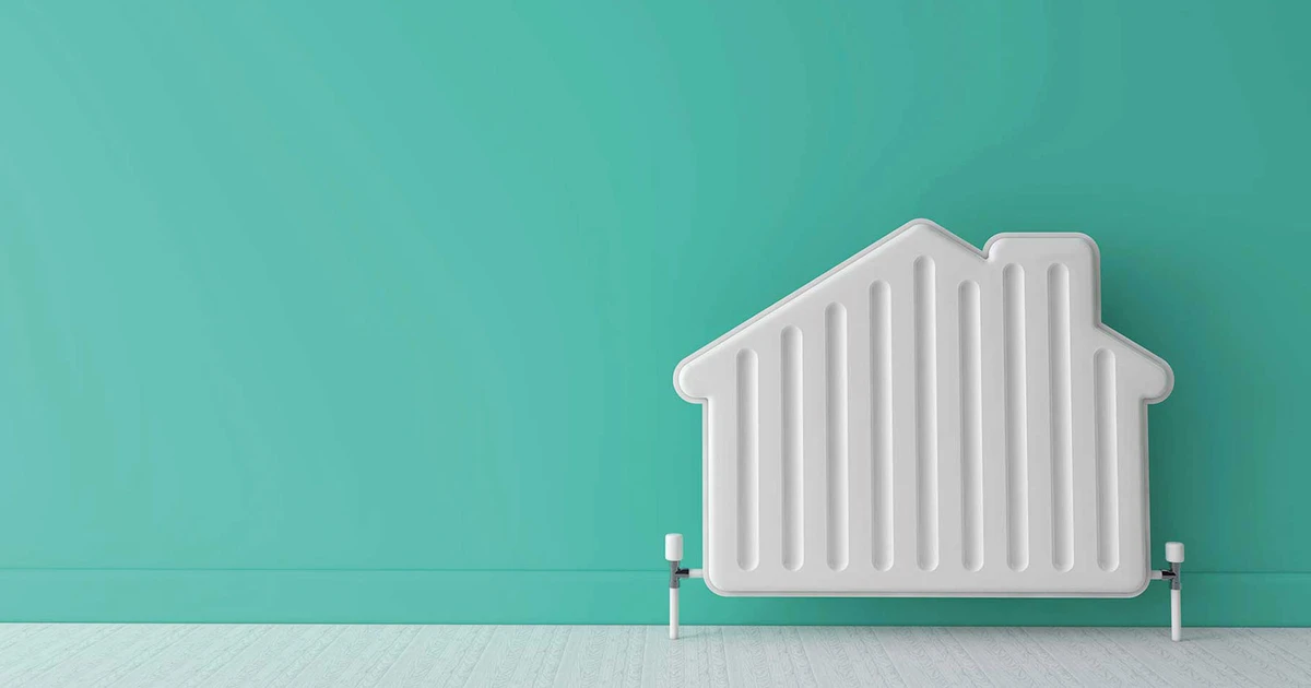 White house-shaped radiator against a teal-coloured wall and light wooden floor.