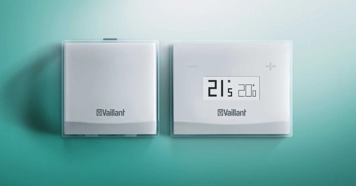 Modern white Vaillant boiler thermostats on a teal wall. One displays 21°c actual and 20°c set temperature.